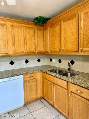 kitchen featuring dishwasher, sink, light tile patterned floors, and stone countertops