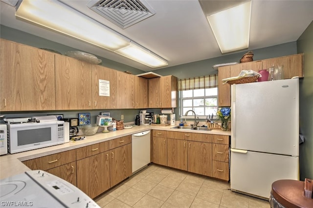 kitchen featuring white appliances, sink, and light tile floors