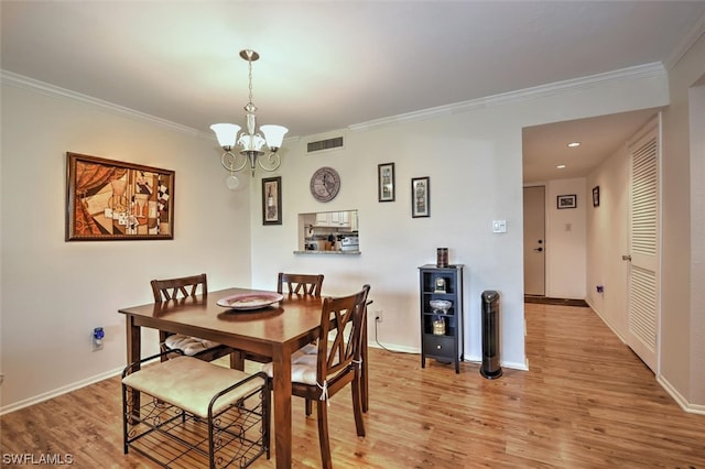 dining area featuring crown molding, light hardwood / wood-style floors, and a chandelier