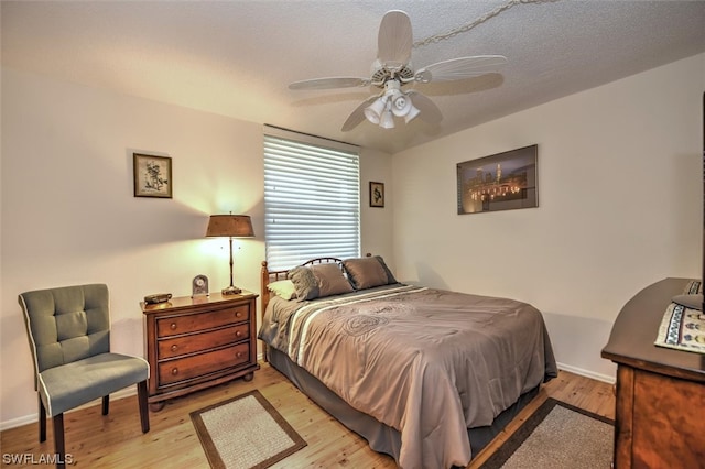 bedroom featuring a textured ceiling, ceiling fan, and light wood-type flooring