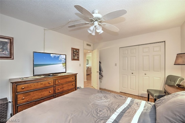 bedroom featuring light hardwood / wood-style floors, a closet, ceiling fan, and a textured ceiling