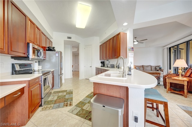 kitchen featuring sink, a breakfast bar area, ceiling fan, kitchen peninsula, and stainless steel appliances