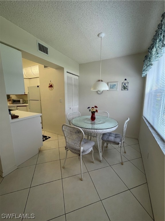 dining space featuring light tile flooring and a textured ceiling