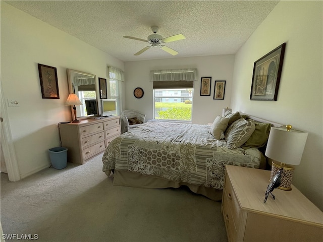 bedroom with ceiling fan, carpet, and a textured ceiling