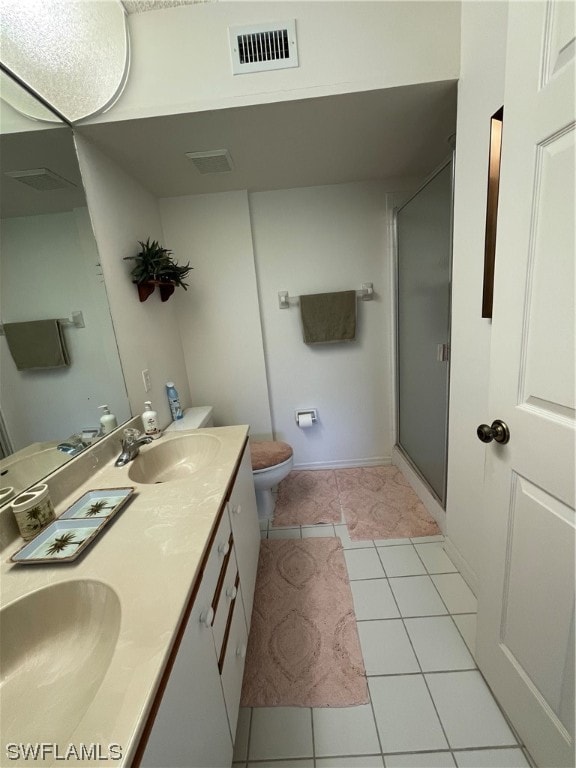 bathroom with an enclosed shower, toilet, tile floors, and double sink vanity