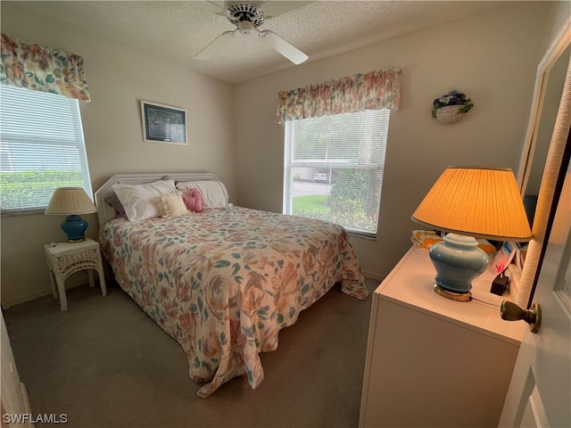 bedroom featuring a textured ceiling, dark colored carpet, and ceiling fan