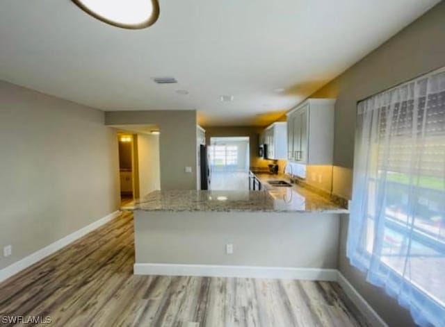 kitchen with light hardwood / wood-style floors, light stone counters, and kitchen peninsula