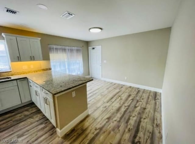 kitchen with tasteful backsplash, light stone countertops, dark hardwood / wood-style flooring, and kitchen peninsula