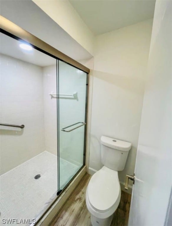 bathroom featuring an enclosed shower, wood-type flooring, and toilet