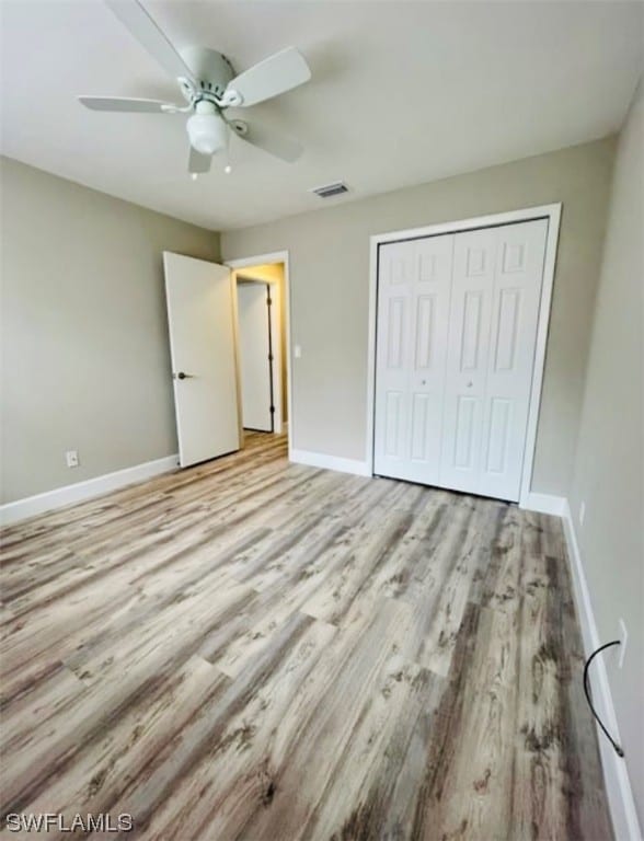 unfurnished bedroom with light hardwood / wood-style flooring, a closet, and ceiling fan