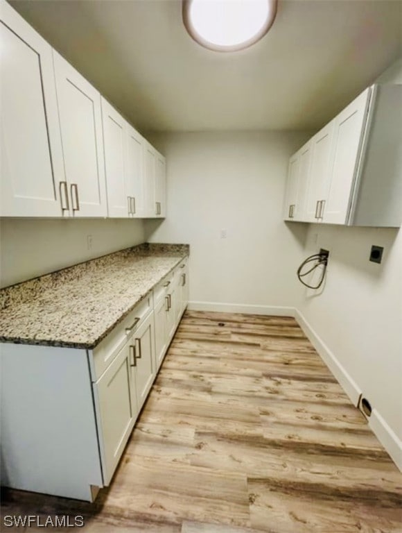 washroom featuring cabinets, electric dryer hookup, and light wood-type flooring