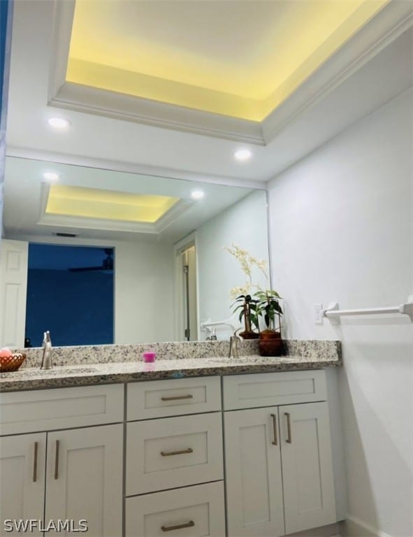 bathroom featuring a raised ceiling, vanity, and ornamental molding