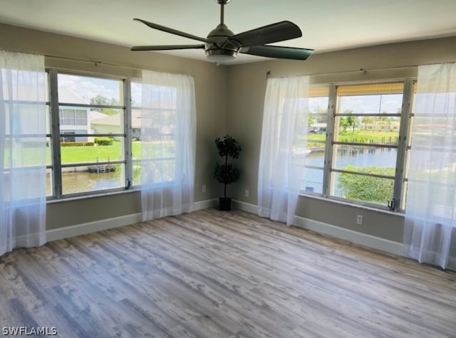 empty room featuring ceiling fan, a water view, and light hardwood / wood-style floors