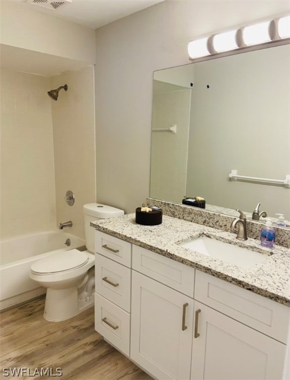 full bathroom with vanity, hardwood / wood-style floors, toilet, and tiled shower / bath