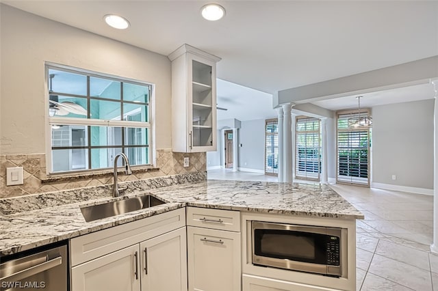 kitchen with decorative light fixtures, white cabinetry, backsplash, appliances with stainless steel finishes, and sink