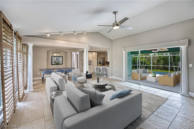 tiled living room with track lighting, vaulted ceiling, ceiling fan with notable chandelier, and decorative columns