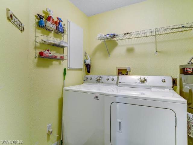 clothes washing area with laundry area, separate washer and dryer, and water heater