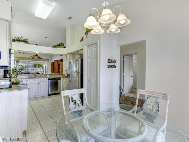 kitchen featuring pendant lighting, a sink, stainless steel appliances, light tile patterned flooring, and a chandelier