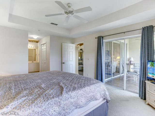 bedroom with a tray ceiling, light carpet, visible vents, and access to outside