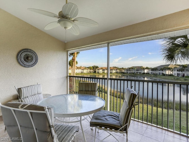 sunroom / solarium with vaulted ceiling, a residential view, ceiling fan, and a water view