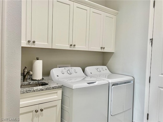 clothes washing area with washer and dryer, cabinets, and sink