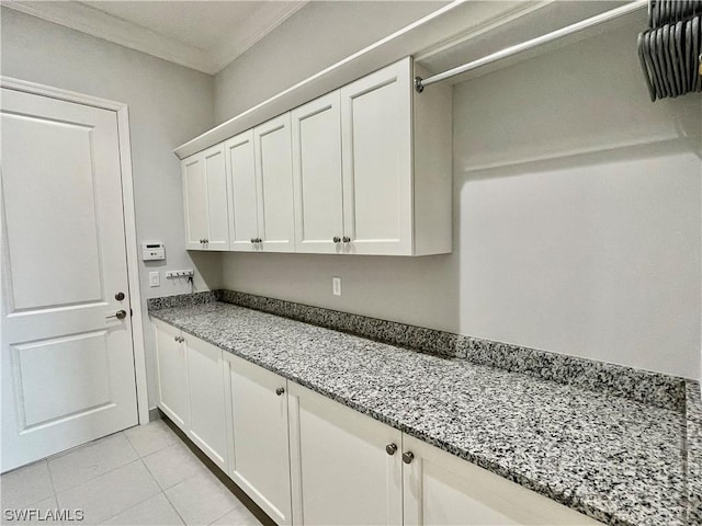 laundry area with light tile patterned floors and crown molding