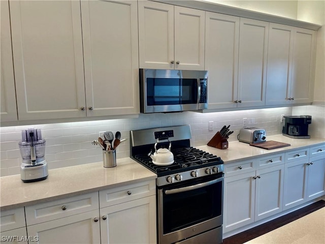 kitchen with light stone countertops, decorative backsplash, white cabinetry, and stainless steel appliances