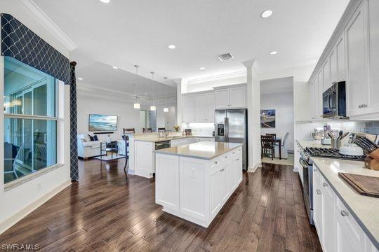 kitchen featuring a center island, hanging light fixtures, dark hardwood / wood-style floors, kitchen peninsula, and stainless steel appliances