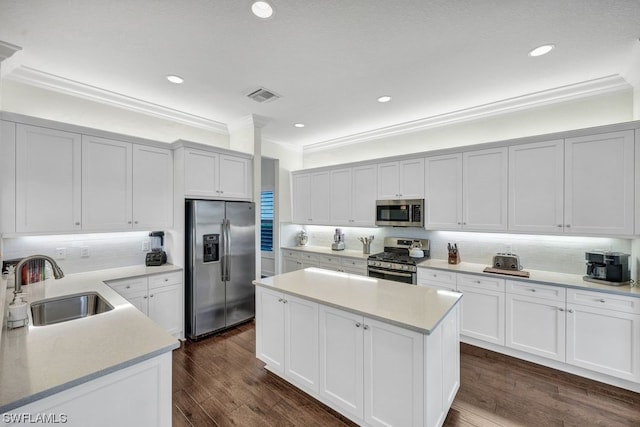 kitchen featuring stainless steel appliances, crown molding, sink, dark hardwood / wood-style floors, and white cabinetry