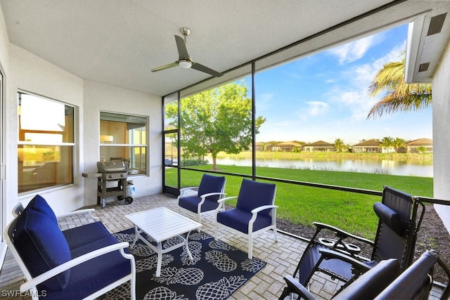 sunroom / solarium with ceiling fan and a water view