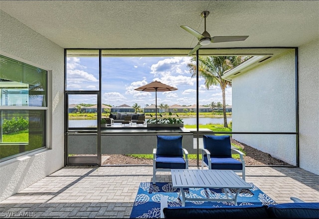 sunroom / solarium with a water view and ceiling fan