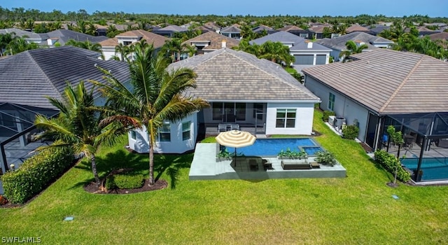 rear view of house with a yard, a patio, and a lanai