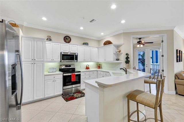 kitchen featuring french doors, ceiling fan, appliances with stainless steel finishes, a breakfast bar, and tasteful backsplash