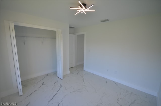 unfurnished bedroom featuring a closet and a chandelier