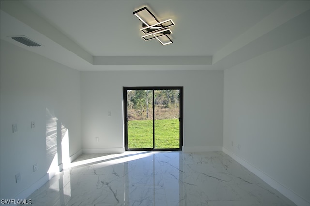 tiled empty room featuring a tray ceiling