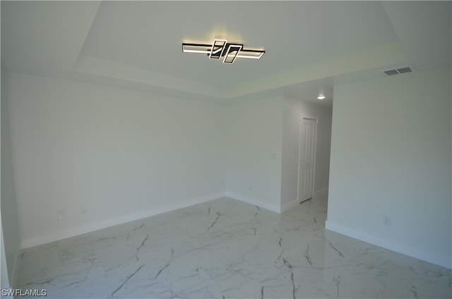 tiled spare room with a tray ceiling