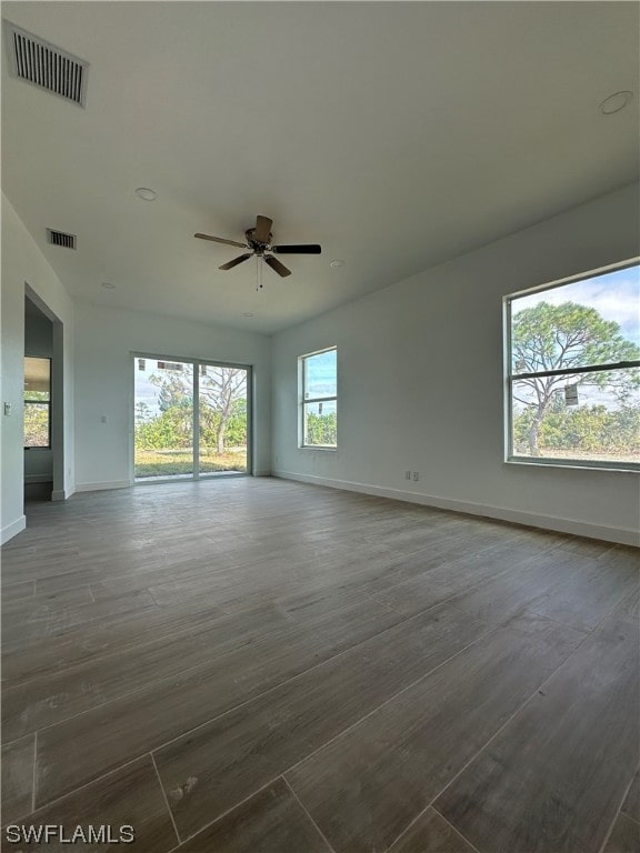 unfurnished room with plenty of natural light, ceiling fan, and dark hardwood / wood-style floors