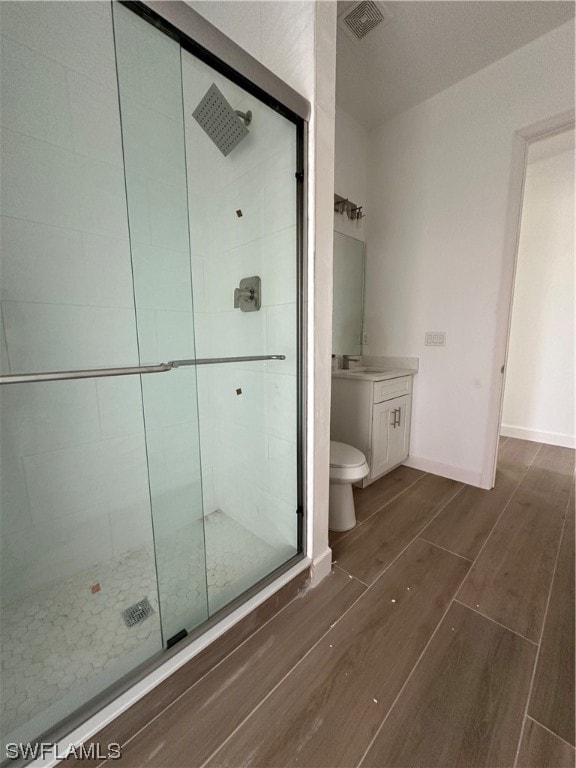 bathroom with wood-type flooring, toilet, an enclosed shower, and vanity