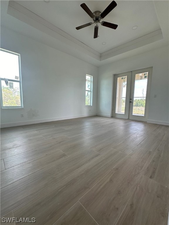 spare room featuring french doors, a tray ceiling, ceiling fan, and light hardwood / wood-style flooring