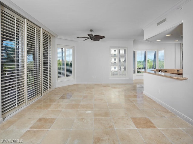 empty room with a wealth of natural light, ceiling fan, visible vents, and crown molding