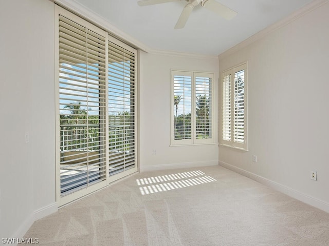 carpeted spare room featuring baseboards, a ceiling fan, and crown molding