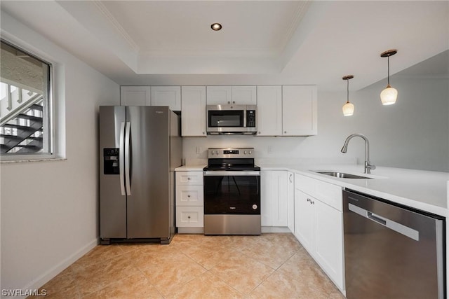 kitchen featuring stainless steel appliances, a tray ceiling, a sink, and light countertops