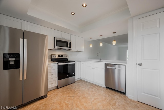 kitchen with a raised ceiling, appliances with stainless steel finishes, pendant lighting, and white cabinetry