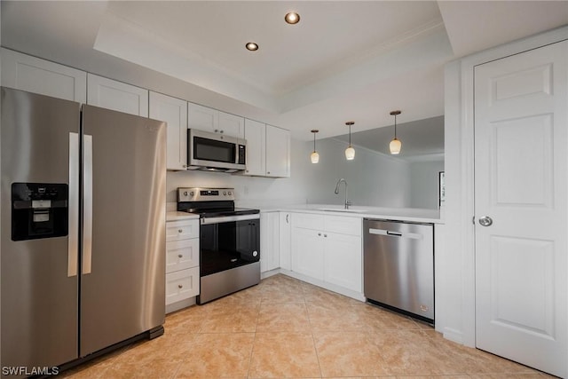 kitchen featuring stainless steel appliances, a tray ceiling, light countertops, and a sink