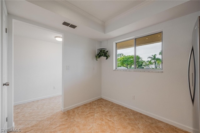 tiled empty room with a raised ceiling and crown molding