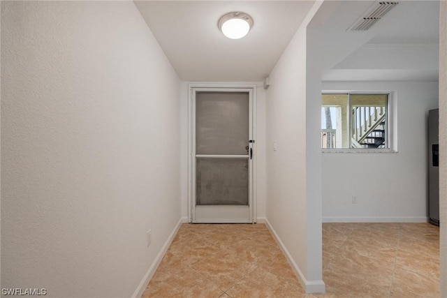 hallway featuring visible vents, baseboards, and light tile patterned flooring