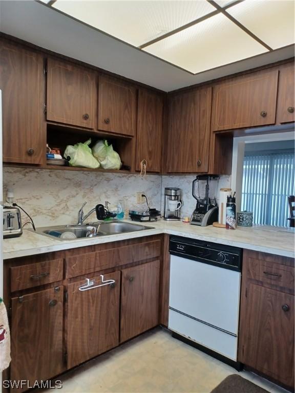 kitchen featuring dishwasher, dark brown cabinetry, sink, and tasteful backsplash