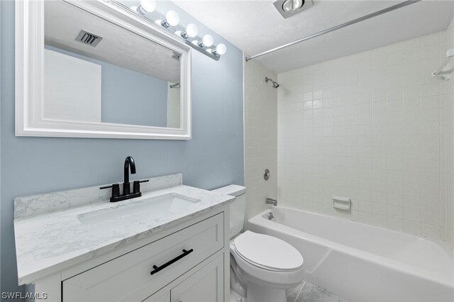 full bathroom featuring tiled shower / bath, vanity, and toilet