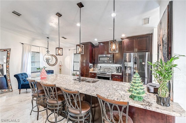 kitchen featuring a kitchen bar, light stone counters, stainless steel appliances, sink, and pendant lighting