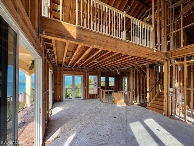 miscellaneous room featuring a towering ceiling, a water view, and french doors